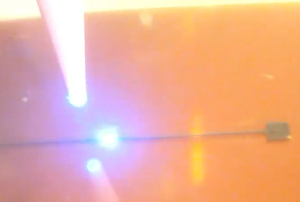 Video still of a close up of laser sintering a NanoJet aerosol printed silver trace on Kapton (polyimide)